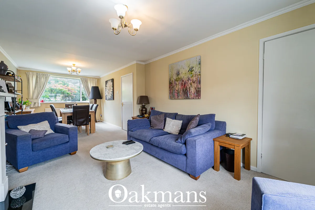 Spacious living room with two blue sofas, marble-topped coffee table, cream walls, yellow and grey ceiling, large window