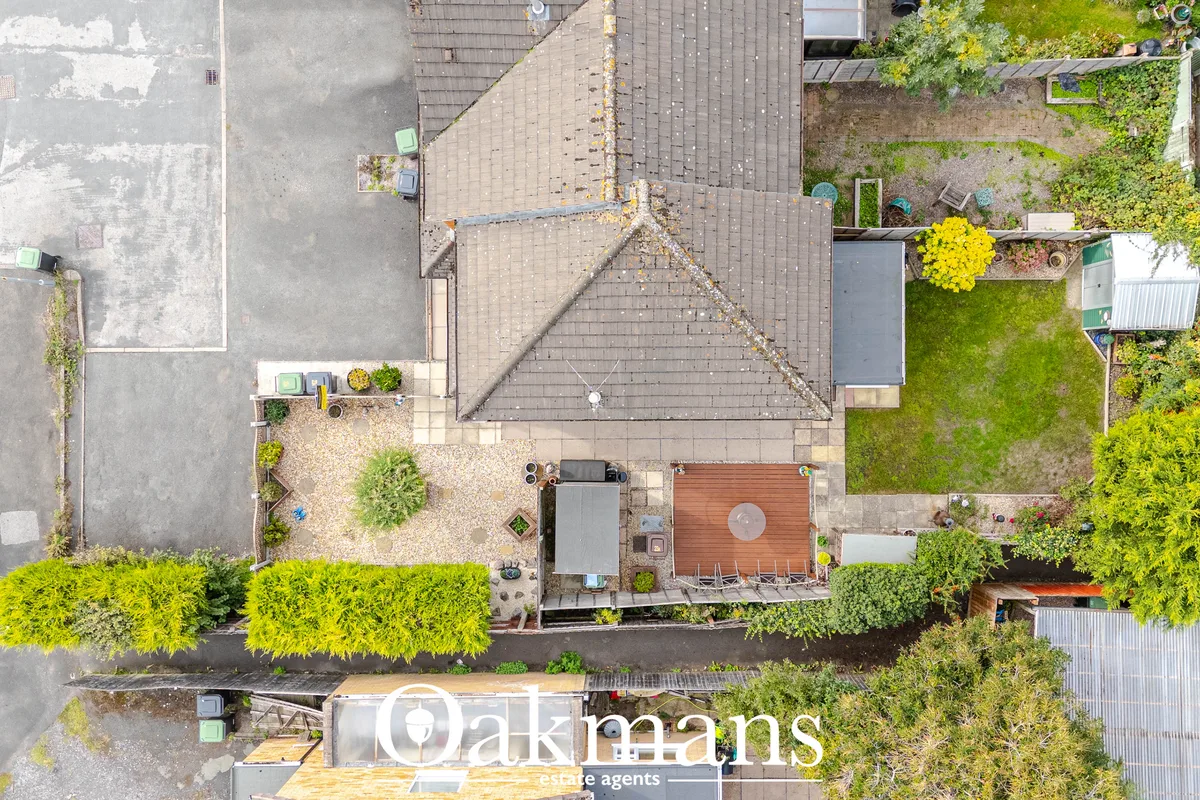 Aerial view of residential property with pitched roof, rear garden with decking, mature hedges and neighbouring properti