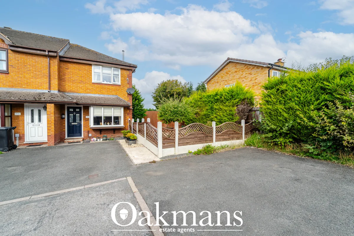 Two-storey brick semi-detached house with driveway, white-framed bay window, dark blue front door and wooden boundary fe