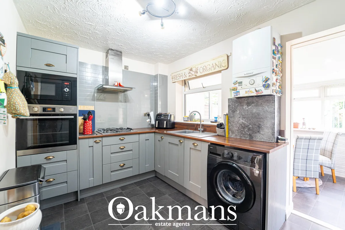 Modern fitted kitchen with pale blue cabinetry, wooden worktops, integrated appliances, ceramic hob, and washer-dryer be