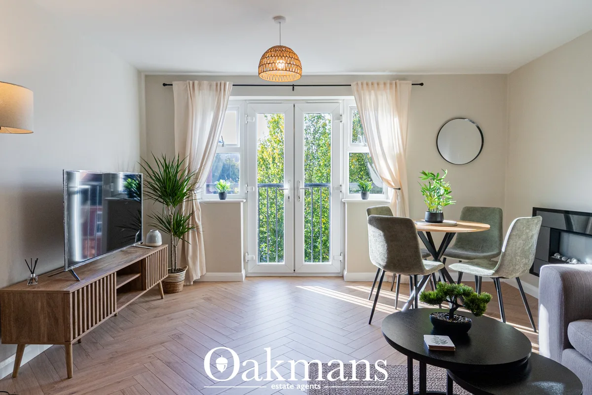 Bright open-plan living space with dining area, woven pendant light, glass balcony doors, neutral furnishings and herrin