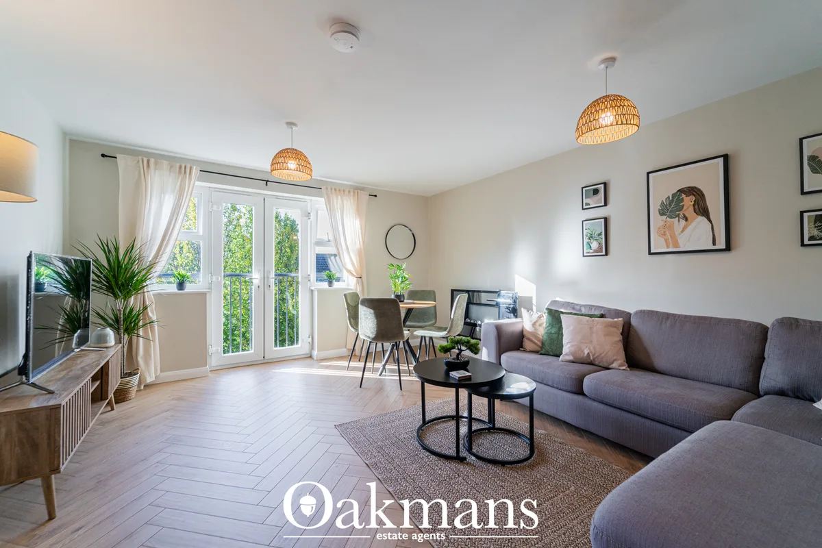 Bright open-plan living room with grey sofa, woven pendant lights, dining area, large windows with patio doors and moder