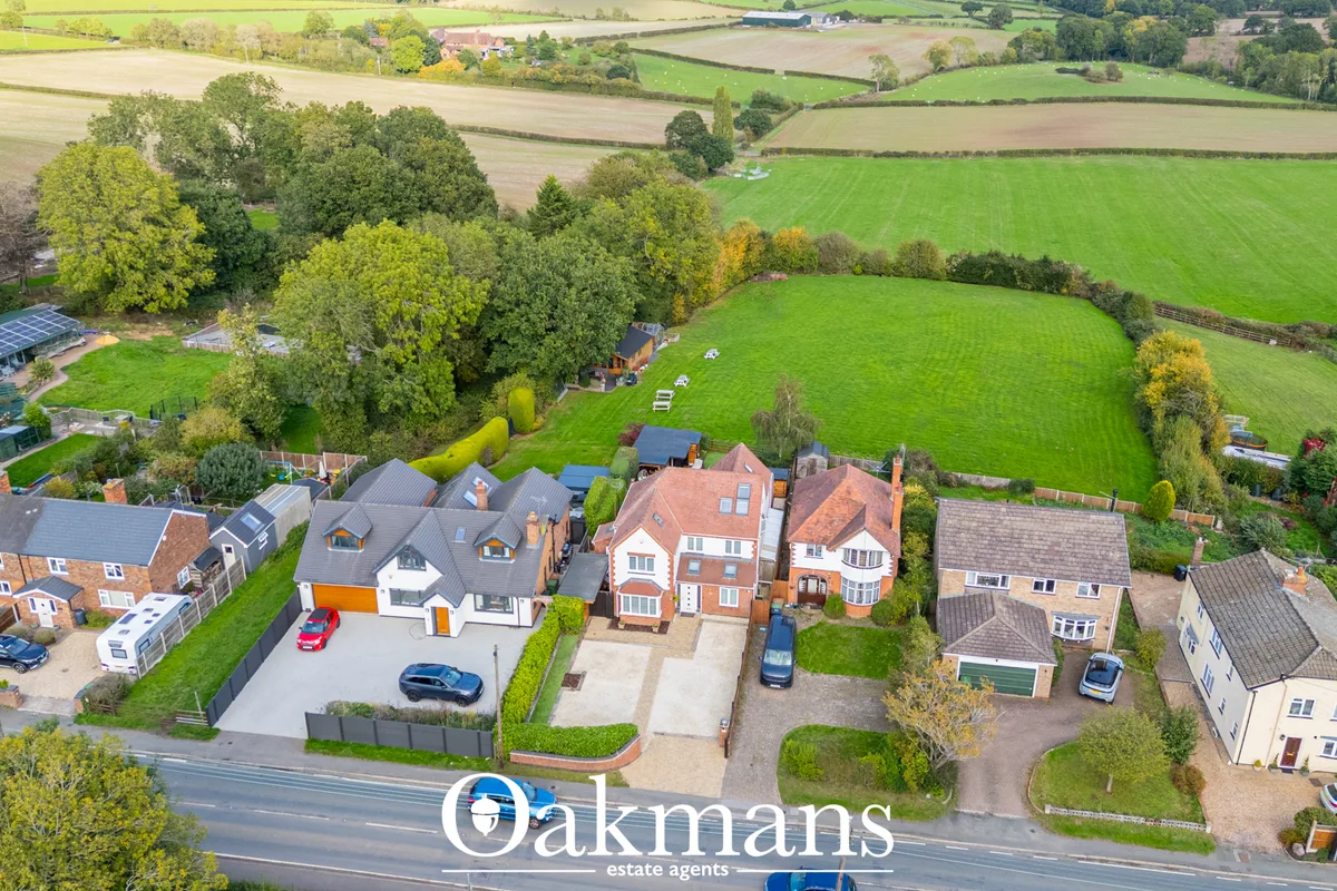 Aerial photograph of residential properties and surrounding countryside with fields, hedgerows and tree-lined boundaries