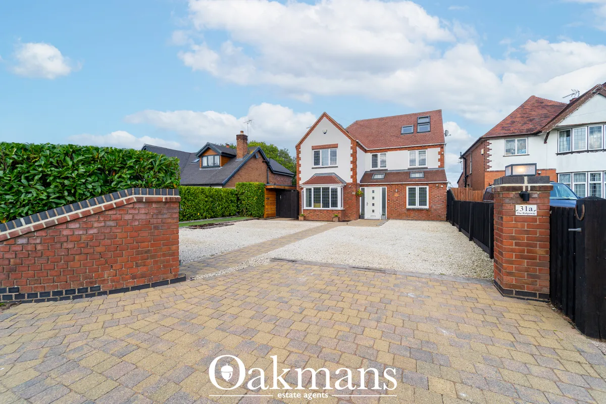 Red brick detached house with driveway, brick boundary wall, manicured hedges and neighbouring properties visible