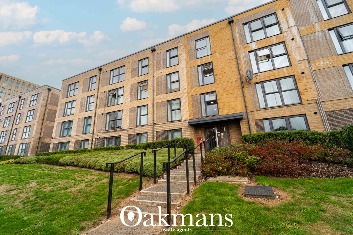 Modern brick apartment building with manicured lawns, hedges and stepped entrance with black railings