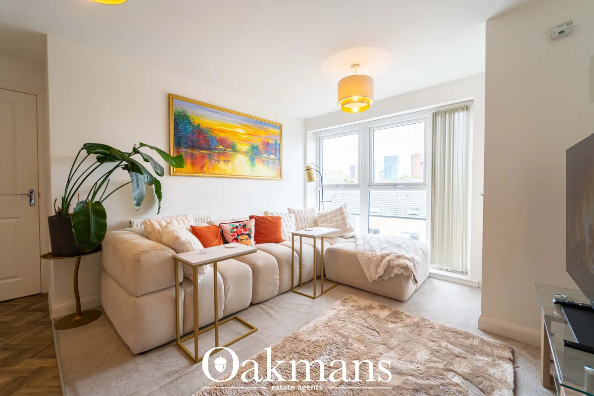 Bright living room with cream modular sofa, orange and patterned cushions, potted plant, wall art, pendant light, floor-