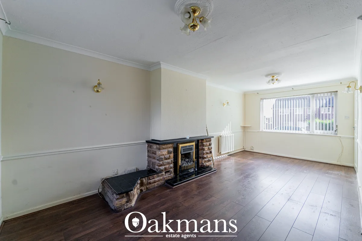 Spacious living room with brick fireplace, electric fire insert, wooden flooring, cream and white walls, radiator and la