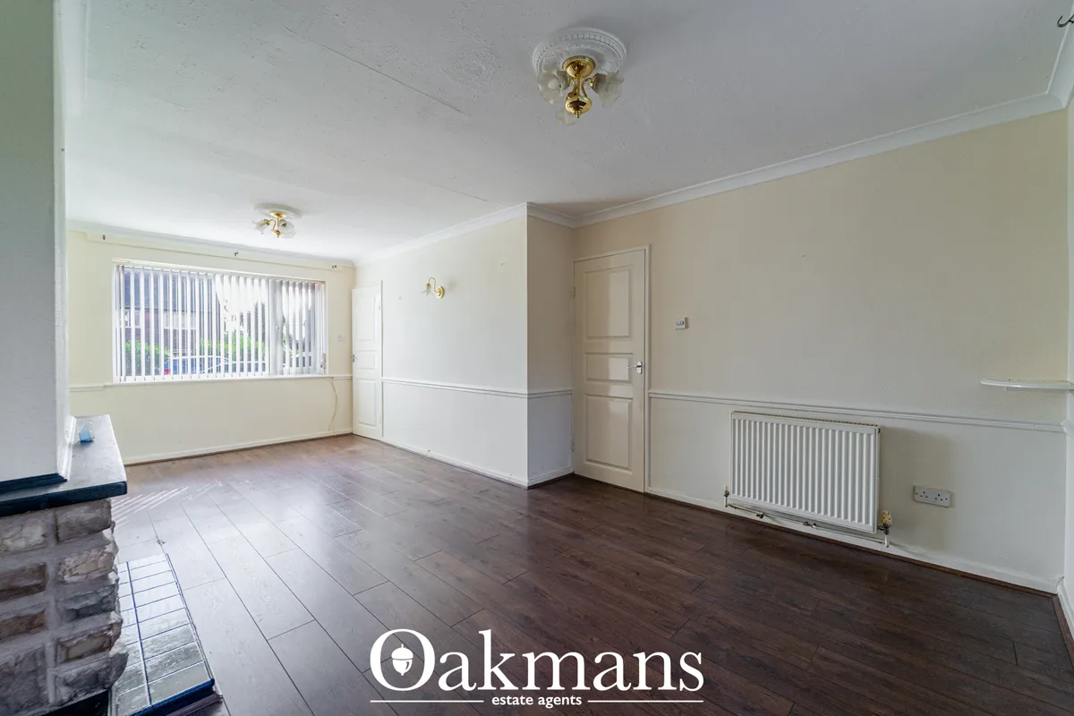 Spacious living room with cream and taupe walls, dark wood flooring, vertical blinds, radiator, ceiling rose and firepla
