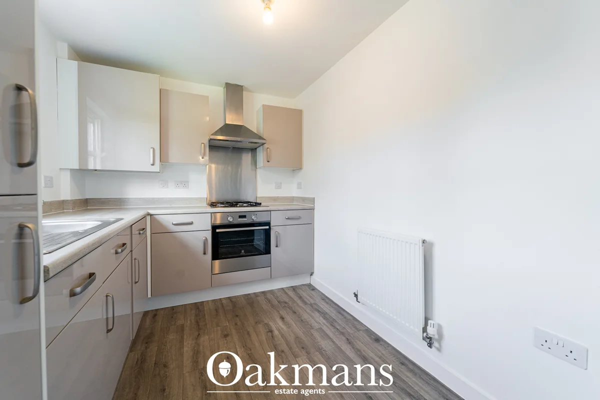 Modern fitted kitchen with cream and beige units, stainless steel appliances, gas hob with extractor hood, wooden-effect