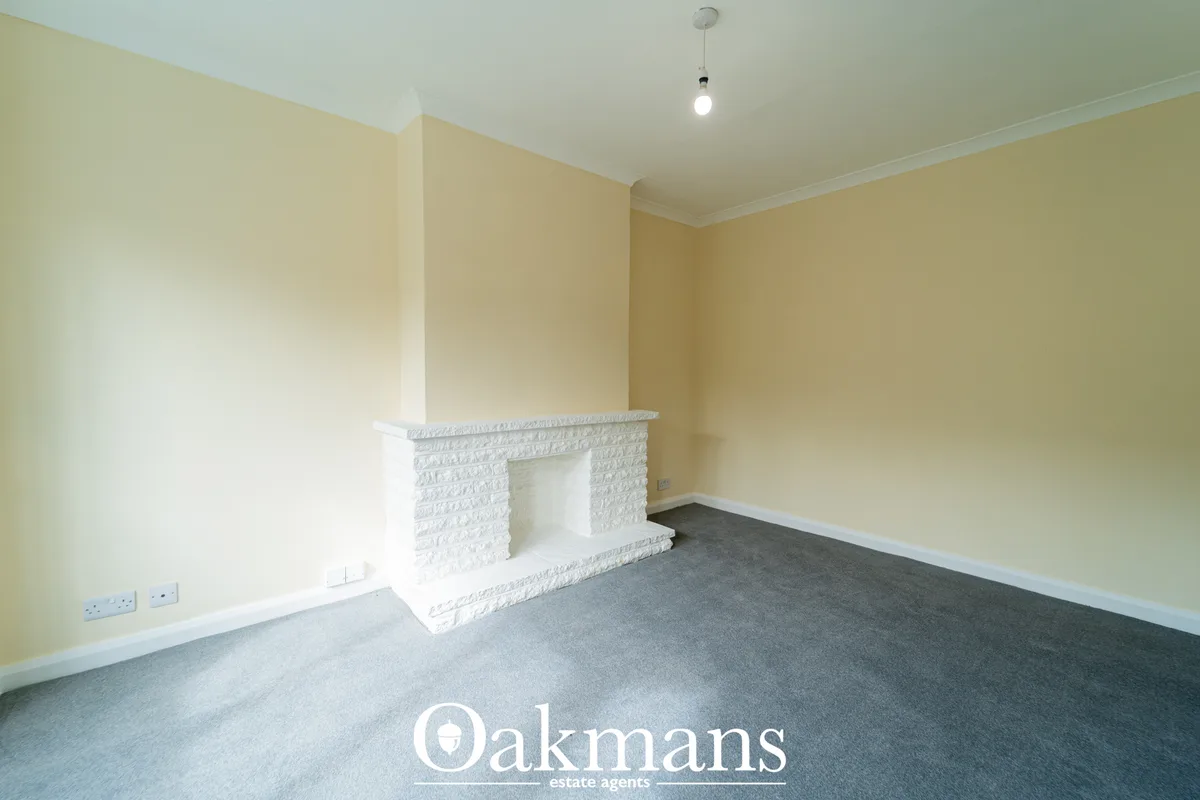 Spacious living room with cream-coloured walls, white textured fireplace feature, grey carpet, pendant light and white s