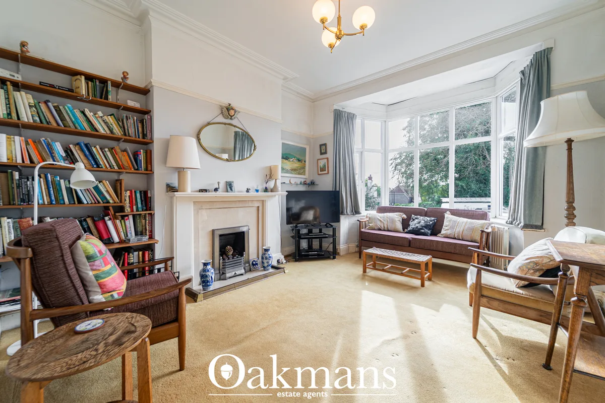 Bright living room with fireplace, built-in bookshelves, brown sofa, wooden furniture, large bay windows with curtains, 