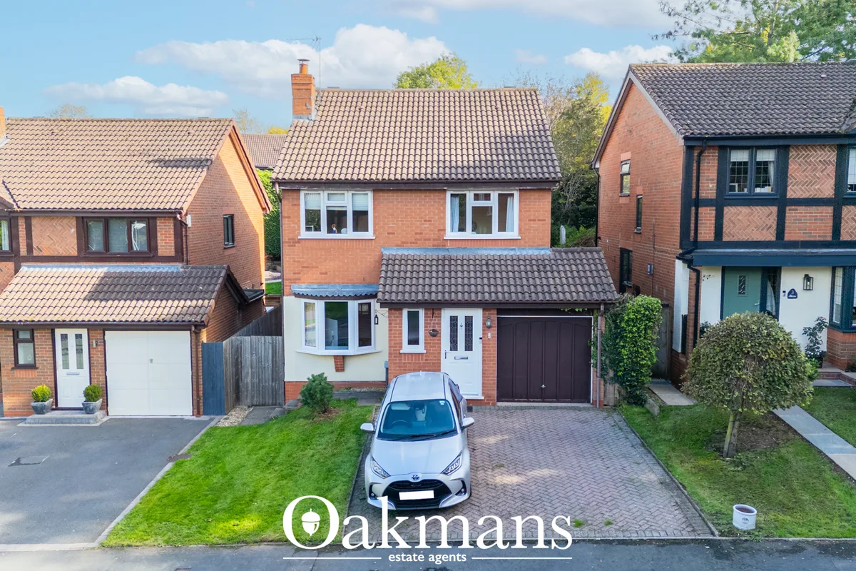 Brick semi-detached house with tiled roof, white windows, dark garage door, paved driveway and manicured garden