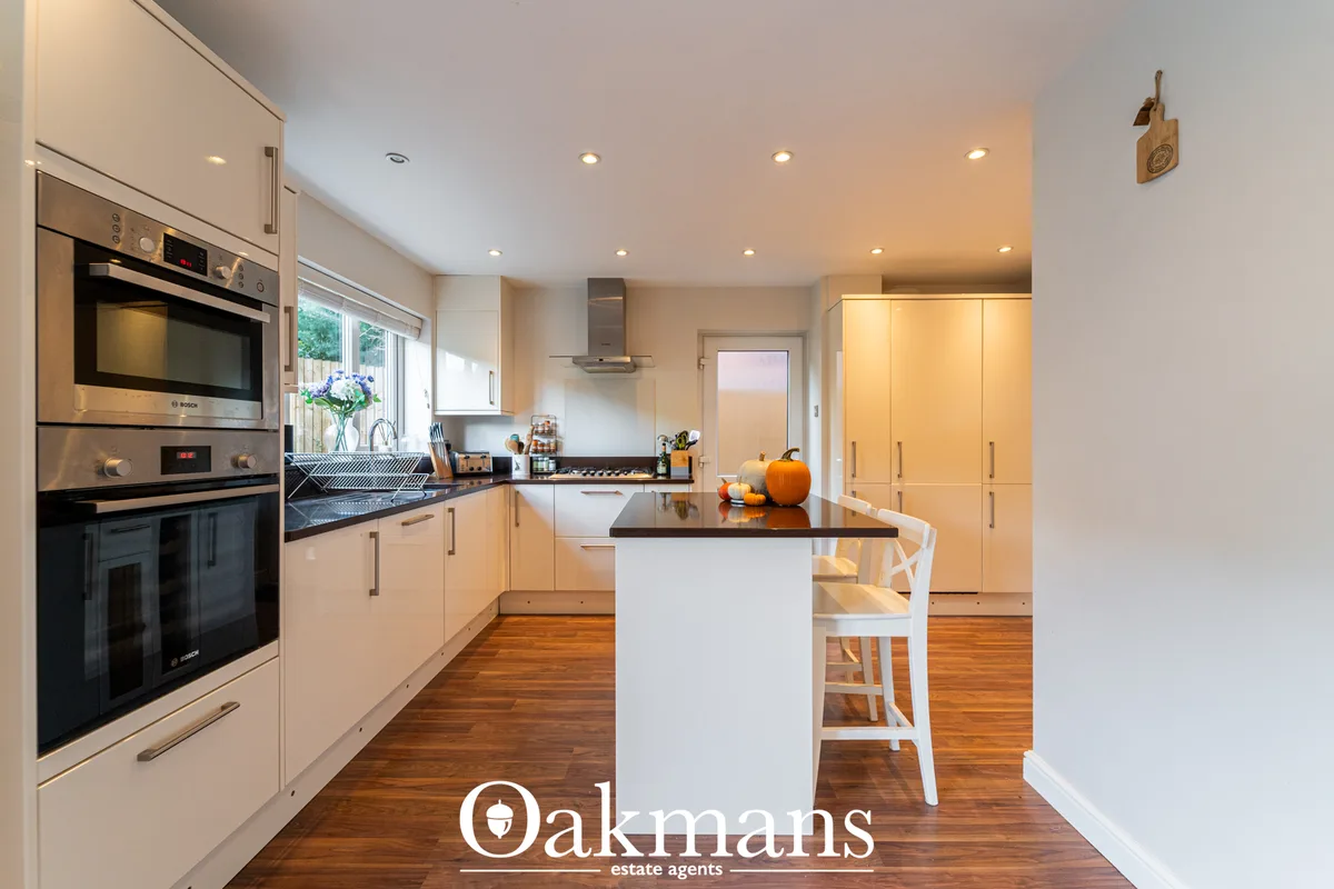 Modern fitted kitchen with cream units, black granite worktops, central island with breakfast bar, built-in appliances, 