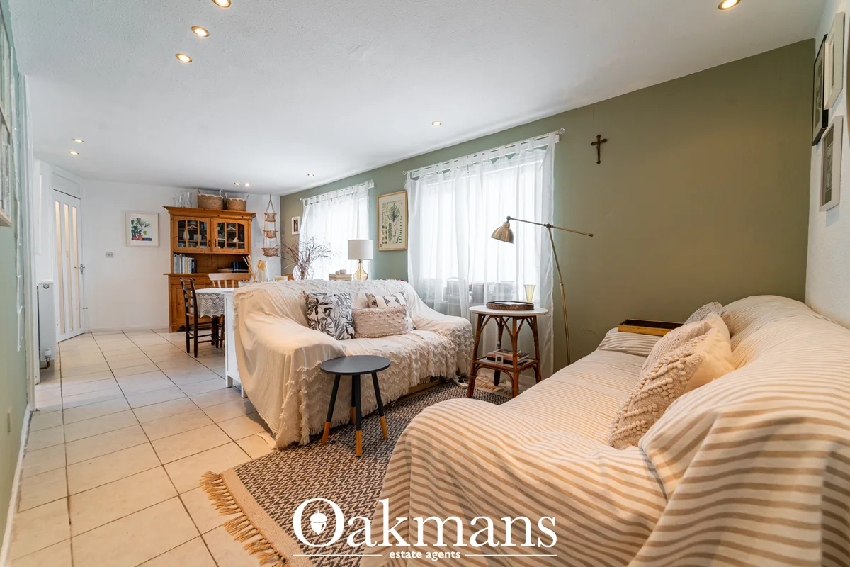 Spacious bedroom with twin beds with striped bedding, sage green accent wall, wooden furniture, desk area, and large win