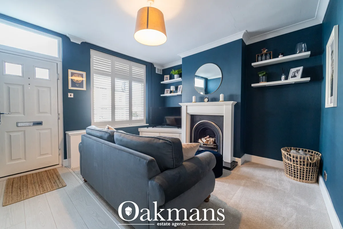 Spacious living room with deep teal walls, dark blue sofa, white fireplace with round mirror, floating shelves, wooden c