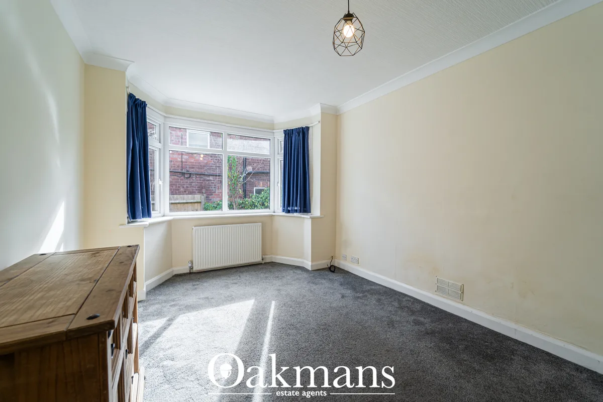 Bright living room with bay window, cream walls, grey carpet, radiator and geometric pendant light