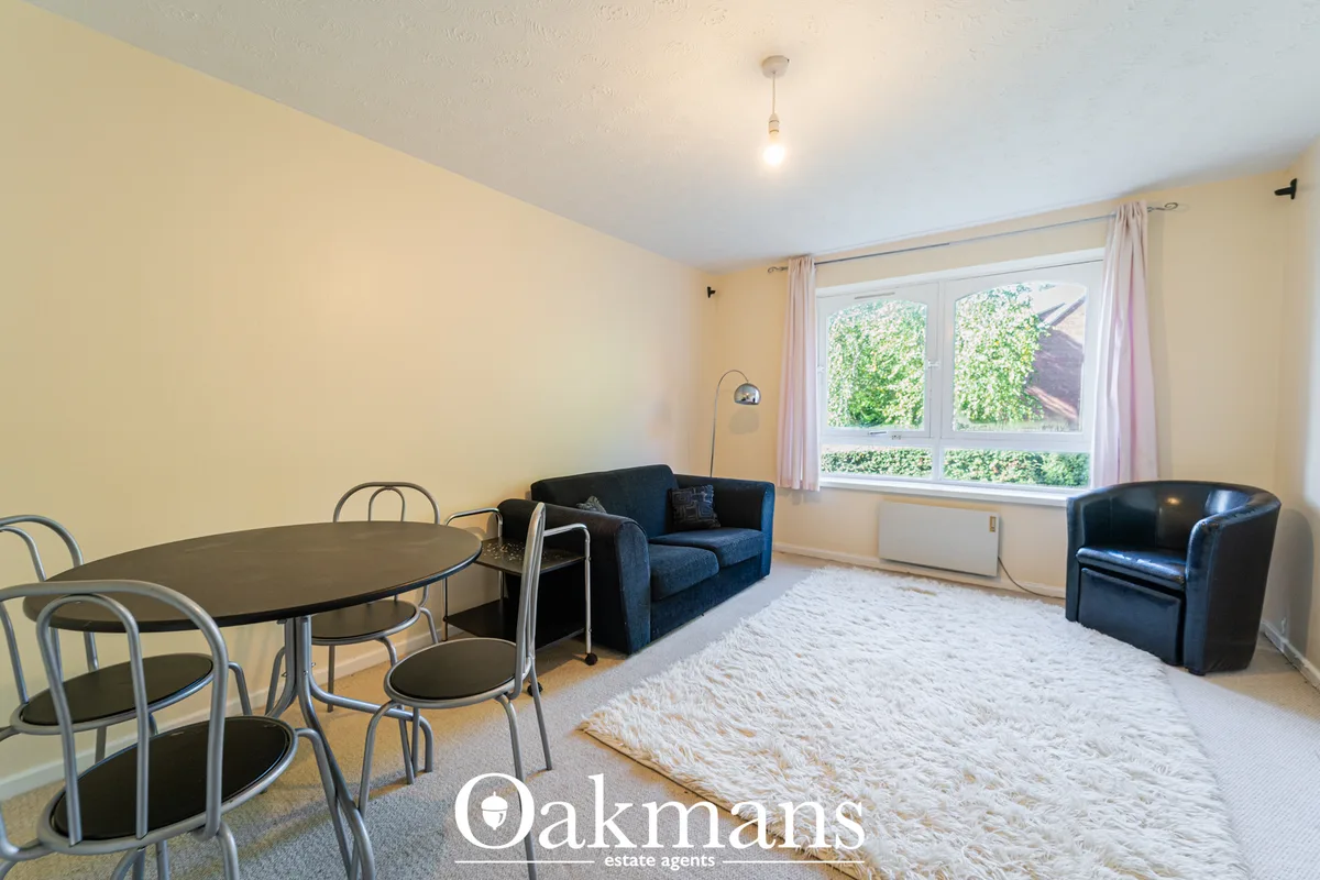 Bright living room with cream walls, blue sofa, black armchair, round dining table with metal chairs, cream rug, and lar