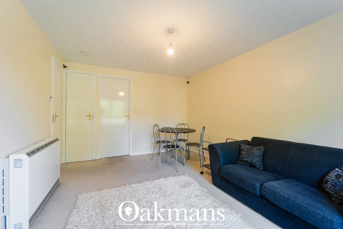 Living room with navy sofa, dining table with chairs, cream carpet, cream walls, and white storage heater
