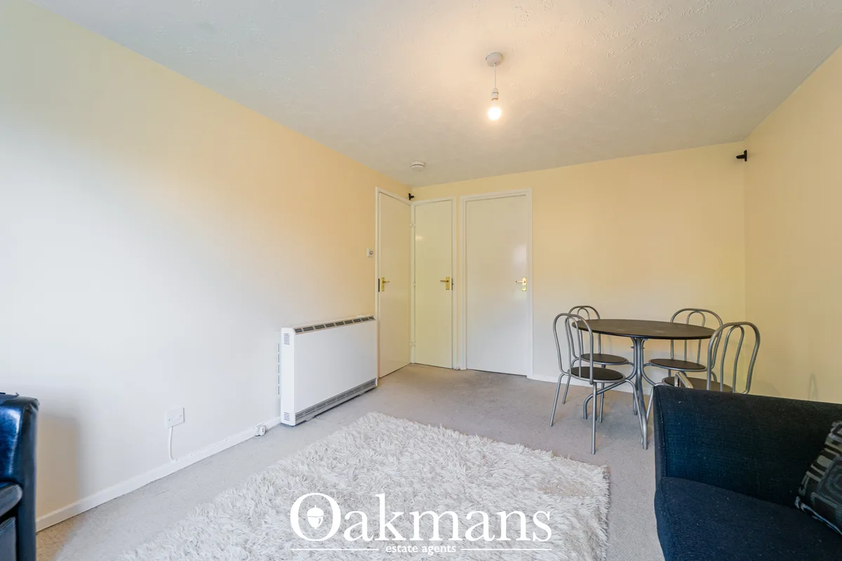 Utility room with cream walls, portable heater, three cream-framed doors, small dining table with chairs, and light carp