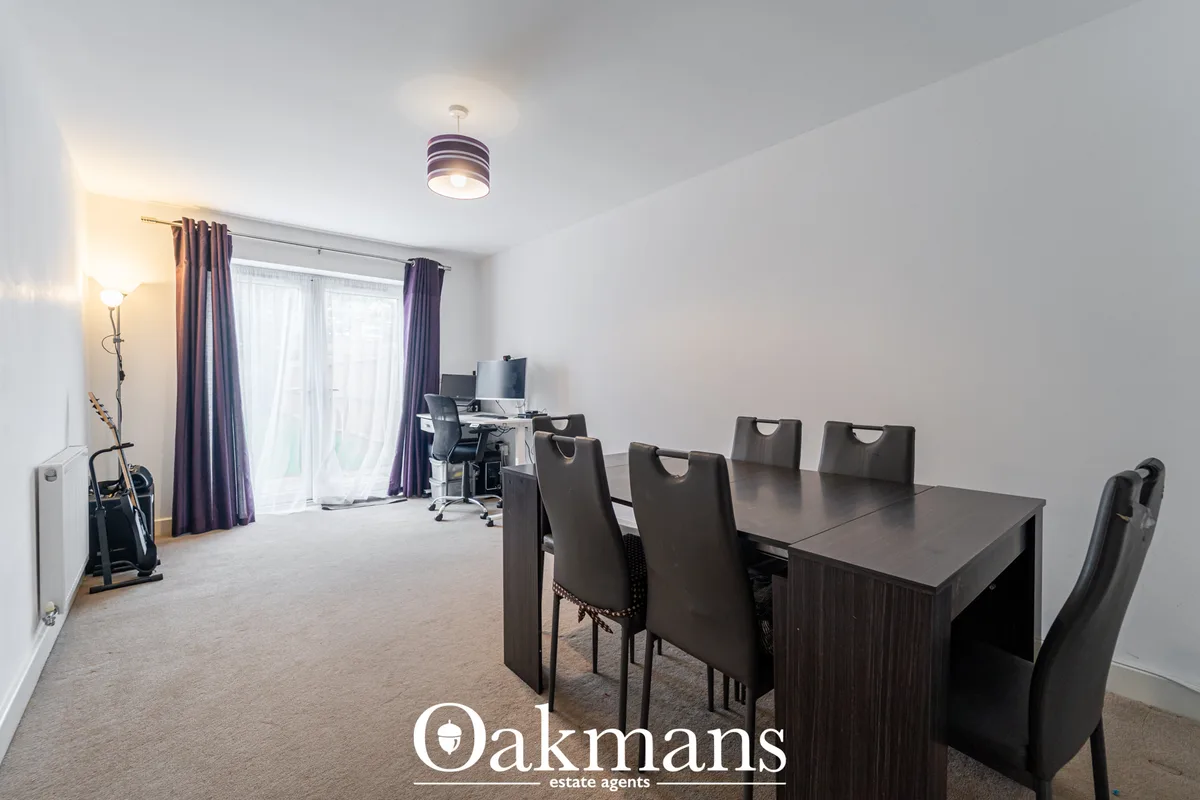 Spacious dining room with dark wood table, six black chairs, ceiling light, windows with purple curtains and study area 