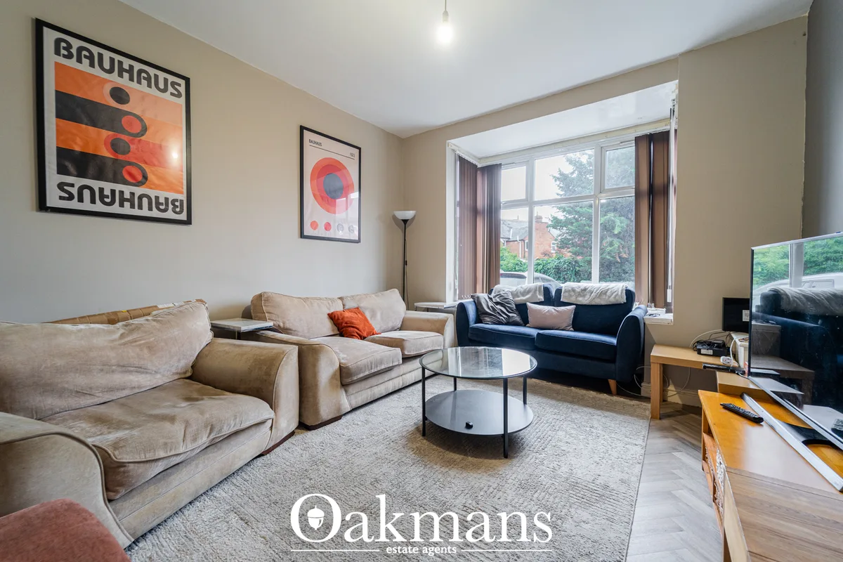 Contemporary living room with beige and navy sofas, round glass coffee table, large windows with city views, wooden floo