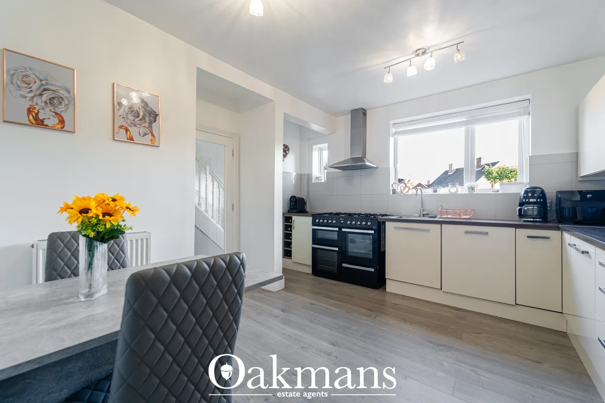 Modern open-plan kitchen with cream units, black range cooker, dark worktops, breakfast bar and dining area with gray qu