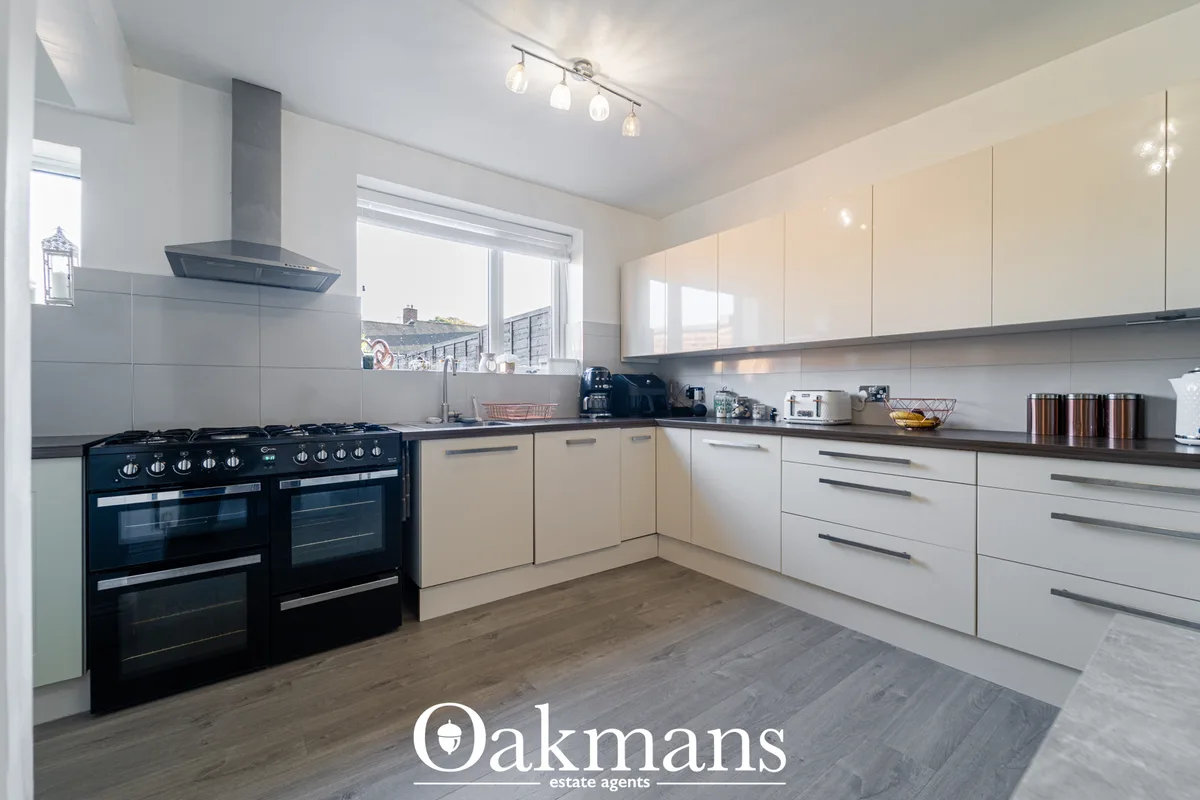 Modern fitted kitchen with cream gloss units, dark granite worktops, black range cooker, stainless steel extractor hood 