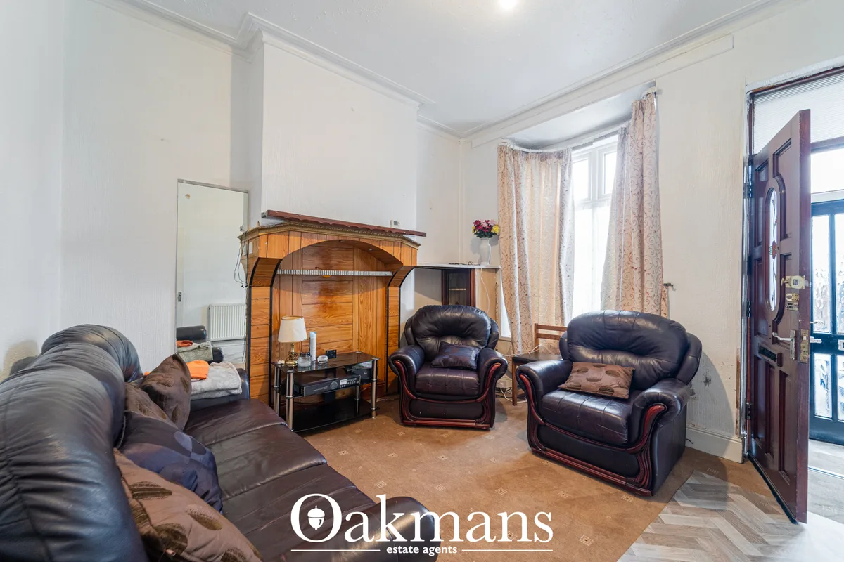 Spacious living room with dark leather armchairs, sofa, wooden wardrobe, bright windows with patterned curtains and wood