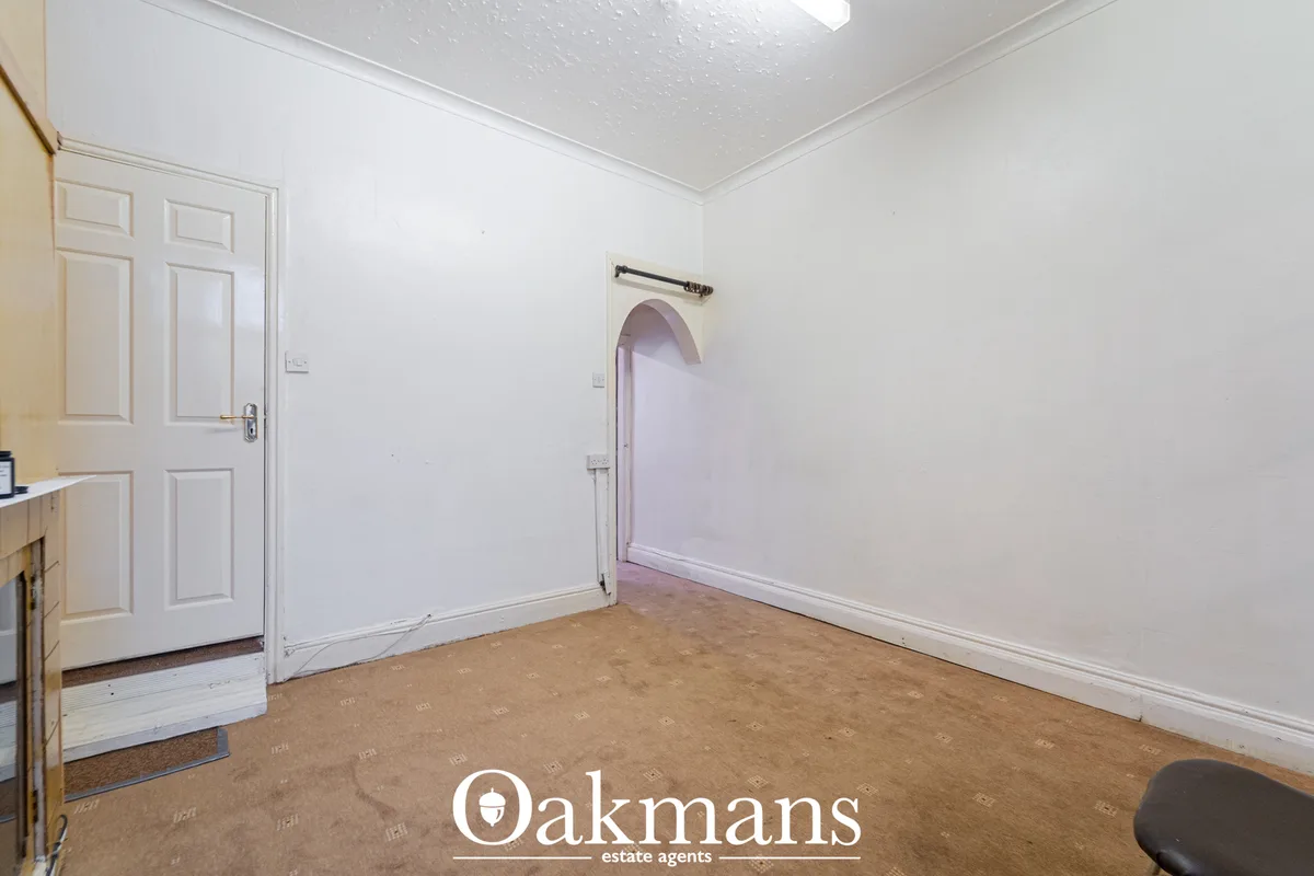 Empty hallway with white walls, cork flooring, white panelled door on left, arched doorway to right, ceiling light, meta