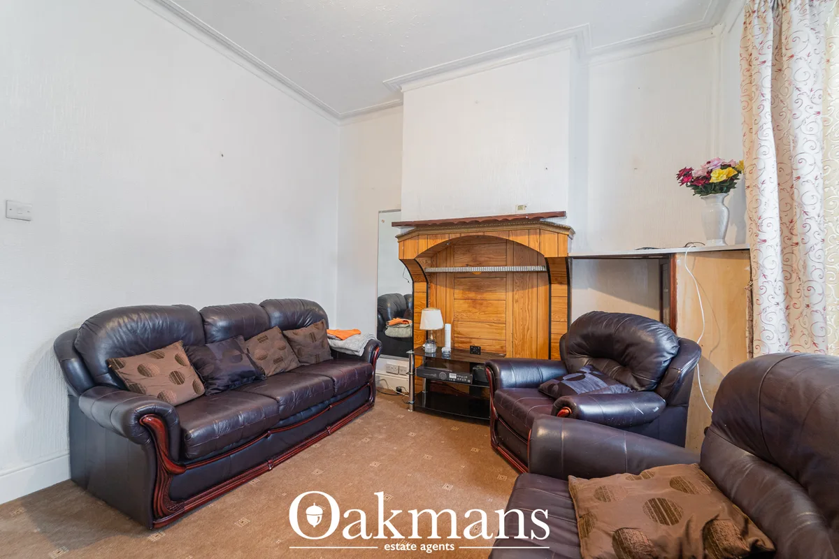 Living room with dark leather sofas, wooden wardrobe, TV entertainment unit, decorative flowers and patterned curtains