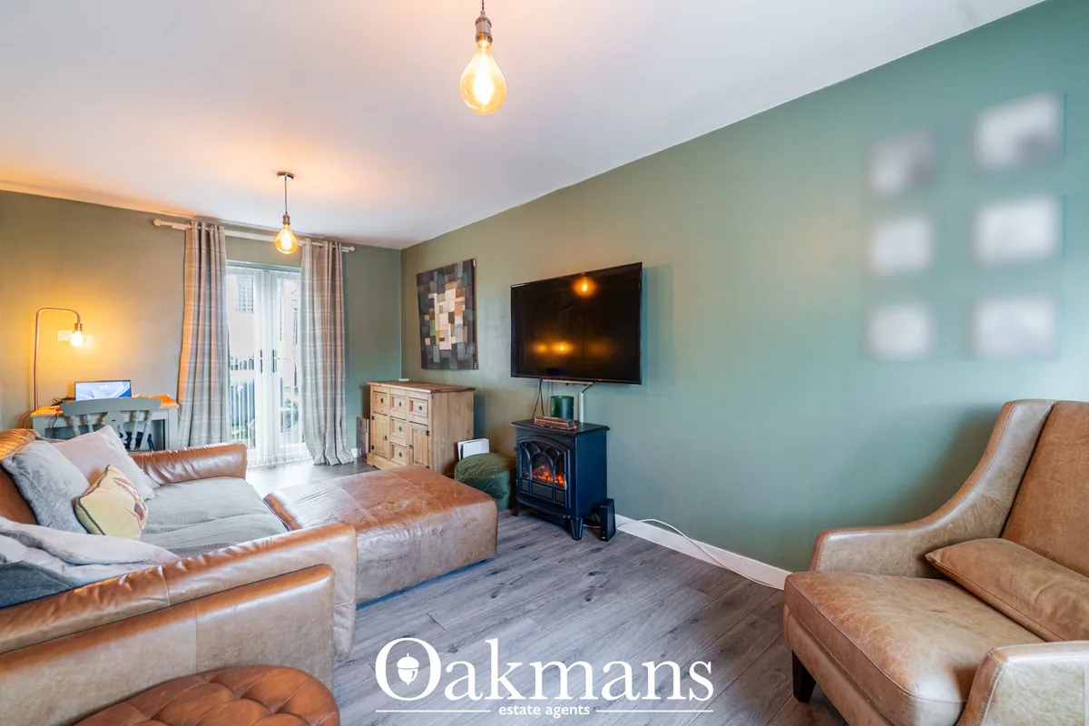 Spacious living room with sage green walls, tan leather sofas, wall-mounted TV, electric stove, wooden furniture and pen