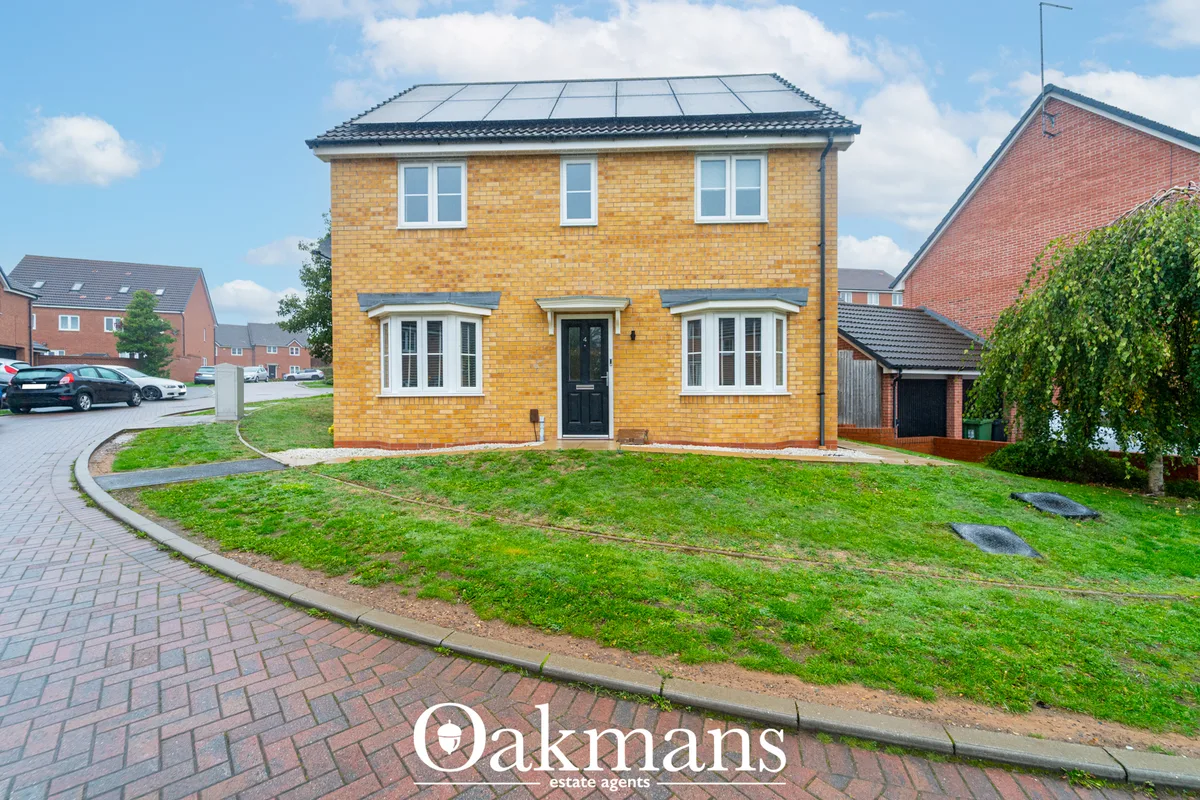 Modern two-storey brick house with golden-yellow brick facade, solar panels on roof, black front door, white-framed wind