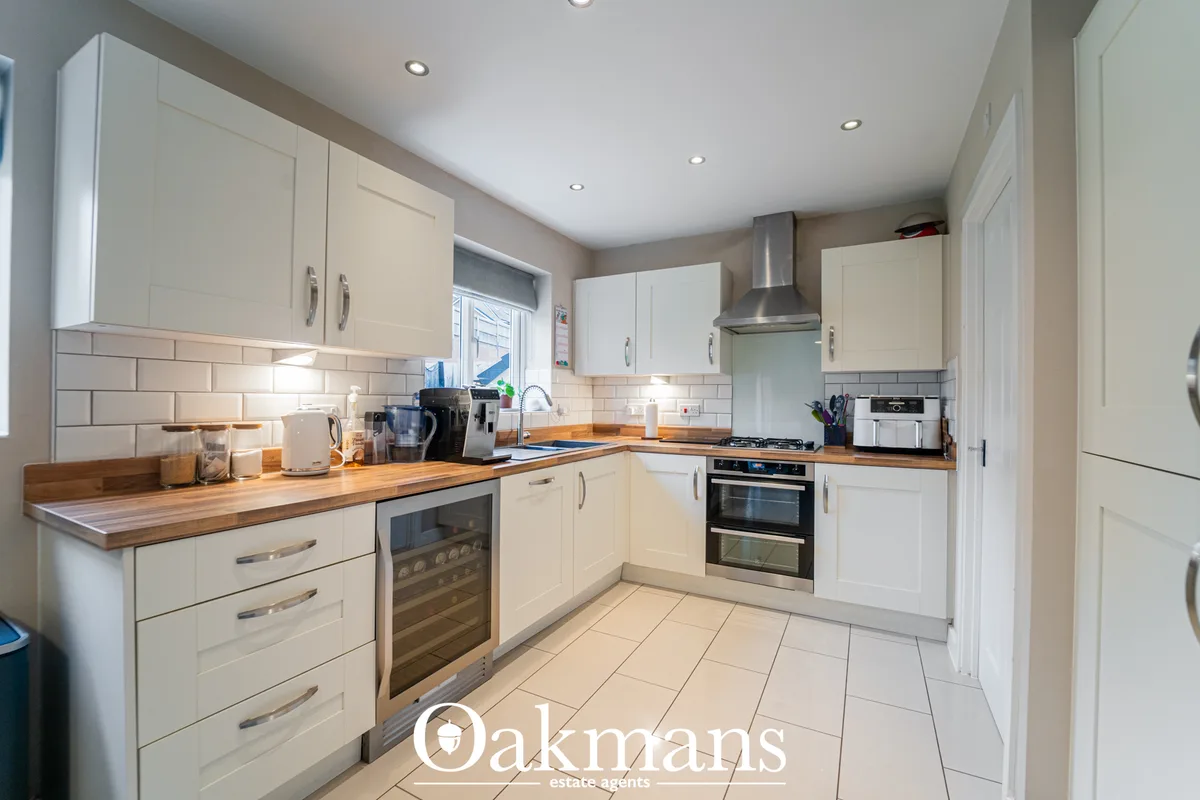 Modern fitted kitchen with cream units, wood worktops, white subway tiles, stainless steel appliances and recessed light