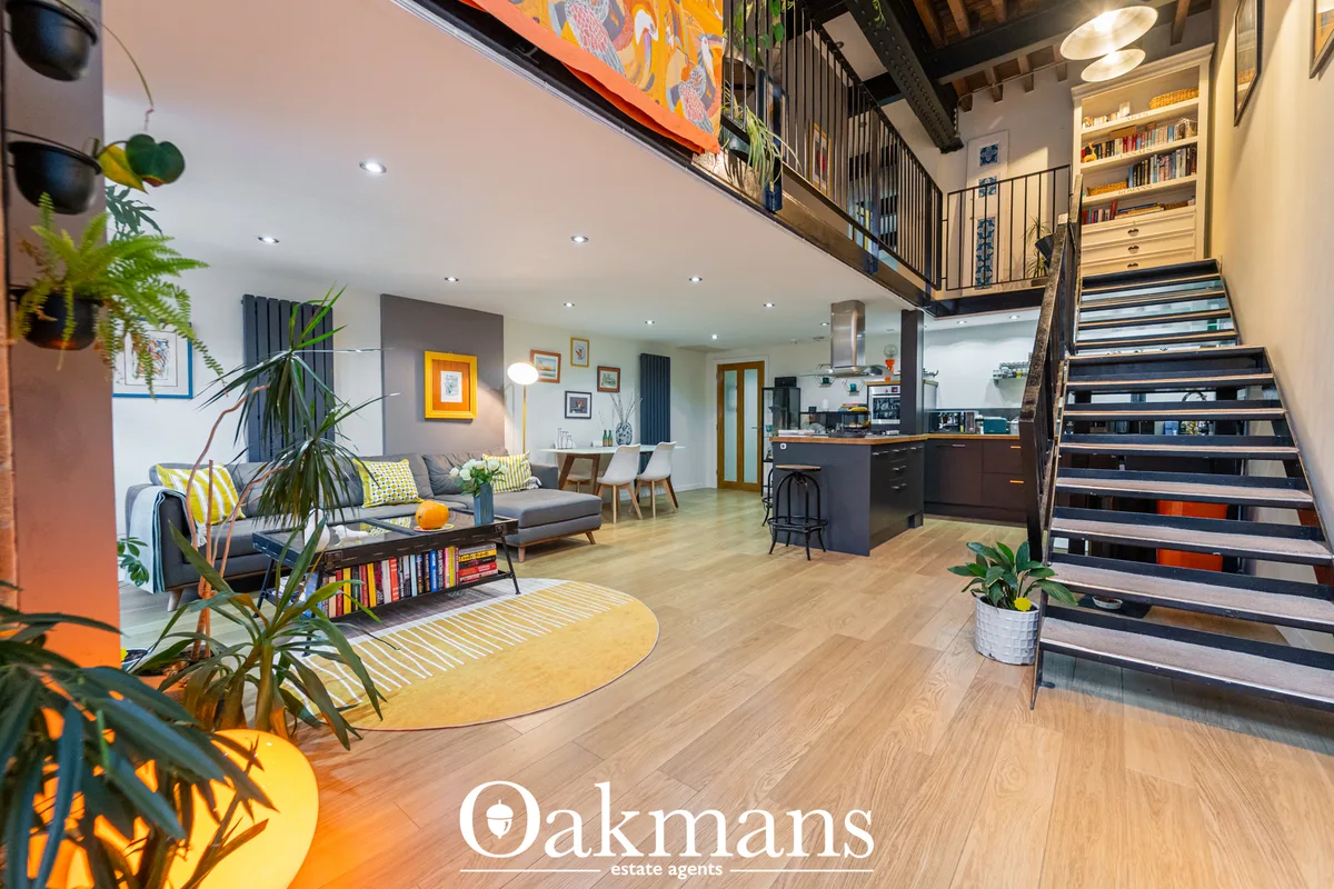 Open-plan hallway and living space with modern staircase, wooden flooring, plants, and contemporary furnishings