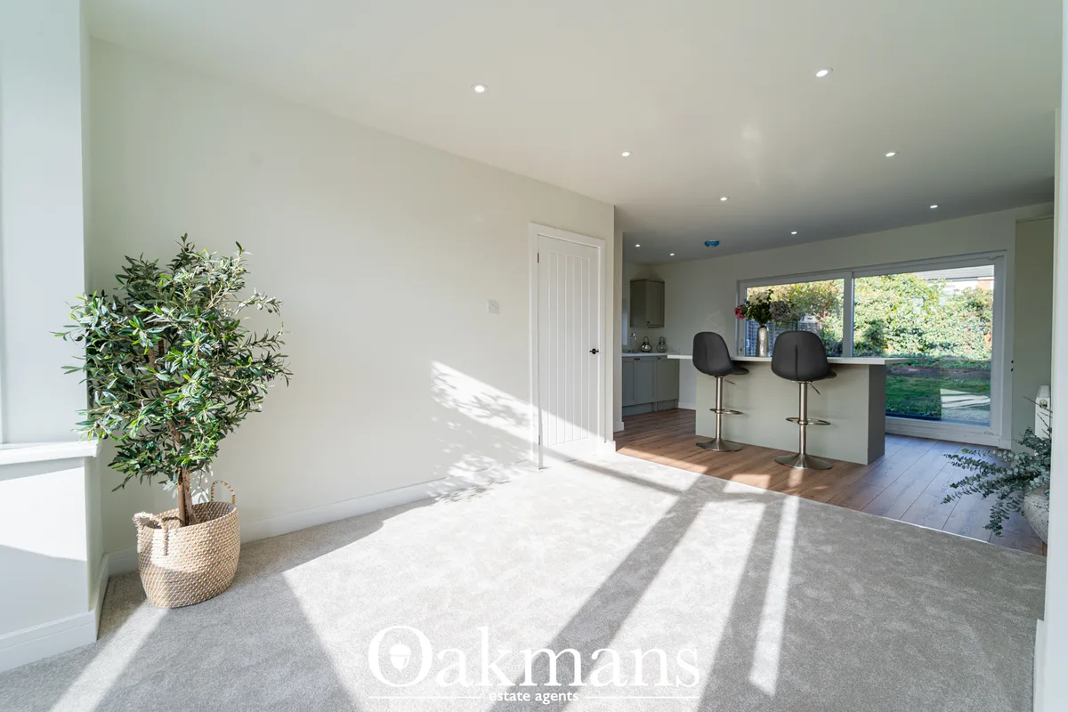 Bright conservatory with grey polished concrete floor, potted plant, white panelled door, grey fitted kitchen units with