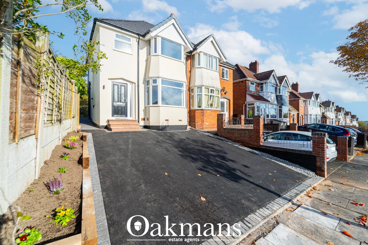 Modern two-storey detached house with cream and brick elevation, driveway, landscaped border and street view of resident