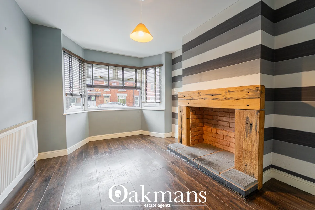 Spacious living room with bay window, striped accent wall, wooden fireplace surround with brick insert, wood flooring, p