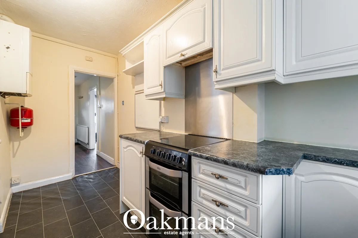 Modern fitted kitchen with white cabinetry, granite worktops, black electric range cooker and stainless steel extractor 