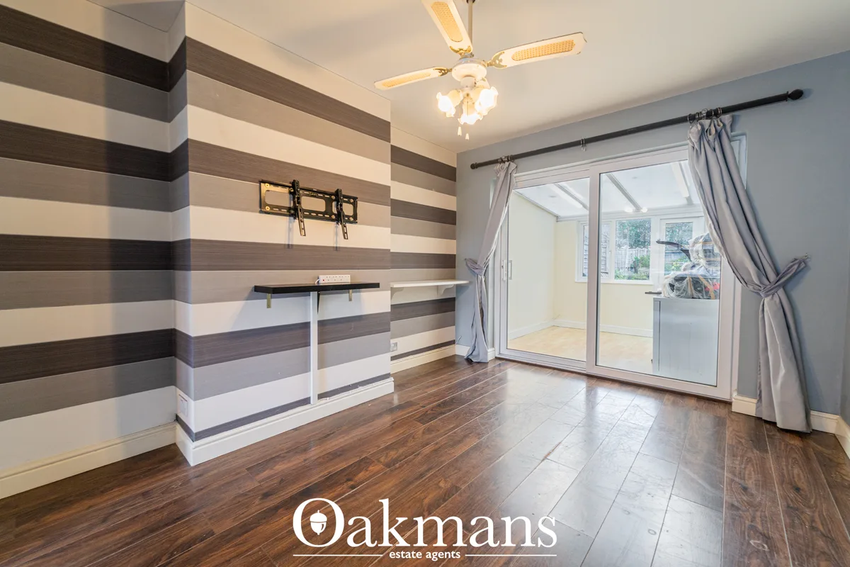 Bright conservatory with striped accent wall, wooden flooring, ceiling fan, wall-mounted TV bracket, glass doors leading