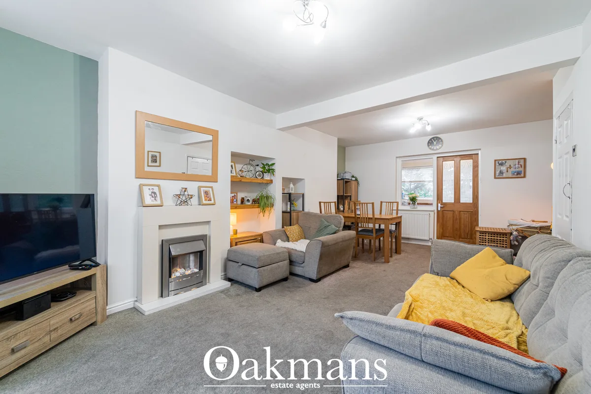 Spacious living room with grey sofas, yellow cushions, fireplace with mirror, TV, wooden furniture, and open-plan dining