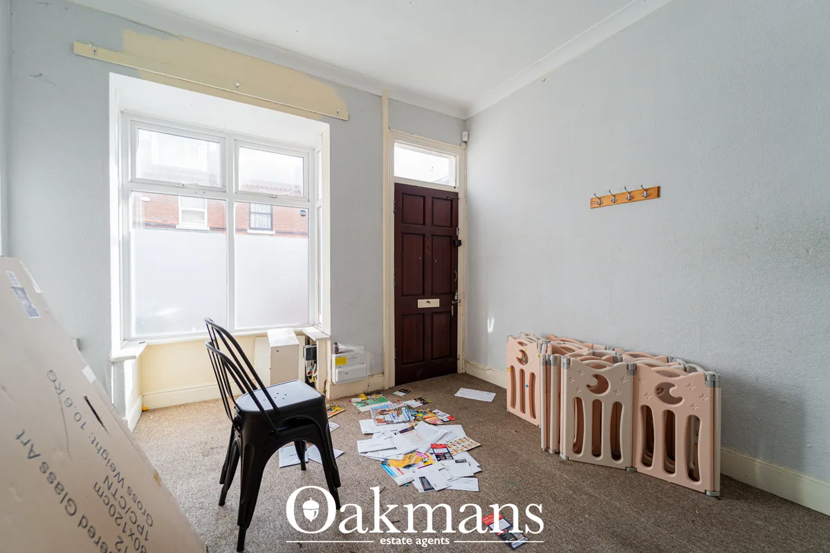 Light hallway with double sash windows, dark wooden door, cork flooring, and radiator panels stacked against wall