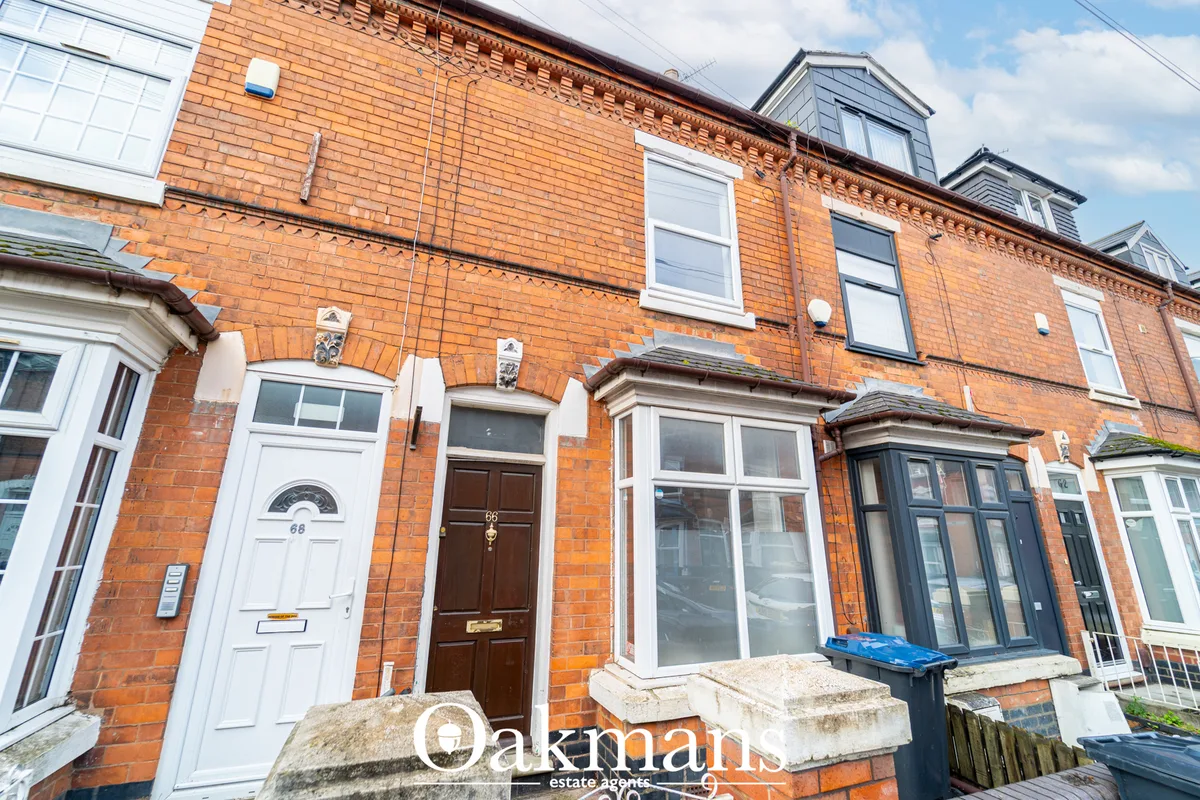 Row of Victorian red brick terraced houses with white-framed windows, dark doors and mansard roof dormers