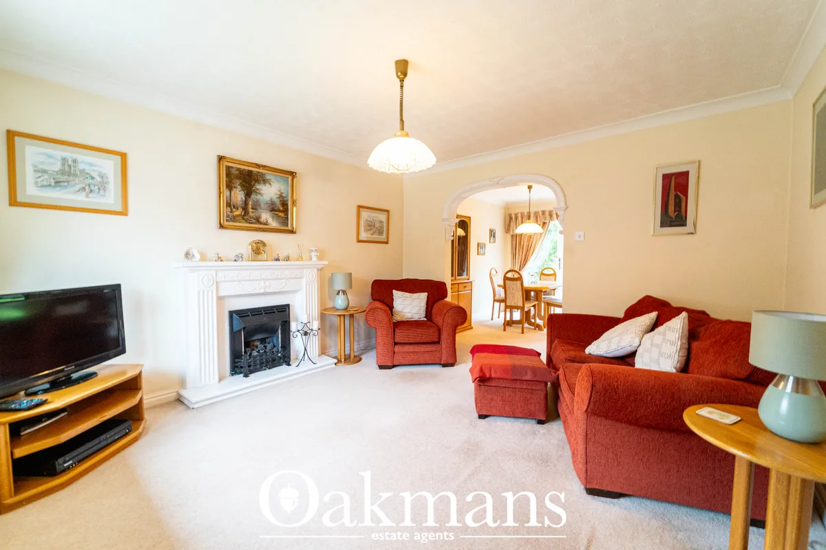 Spacious living room with red upholstered furniture, white fireplace with insert, framed artworks, wooden TV stand, pend