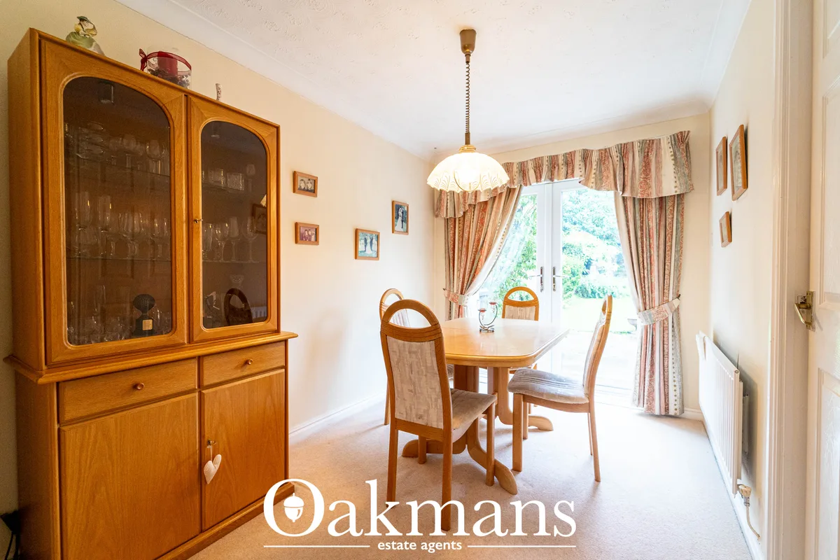 Elegant dining room with wooden table, chairs, traditional dresser with glass doors, patterned curtains and pendant ligh