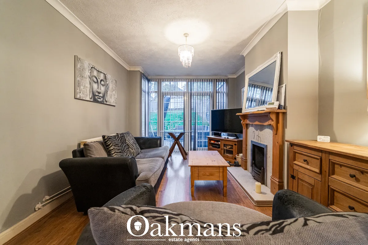 Spacious living room with grey sofas, wooden furniture, fireplace, flat-screen TV, pendant lighting, and glass balcony d