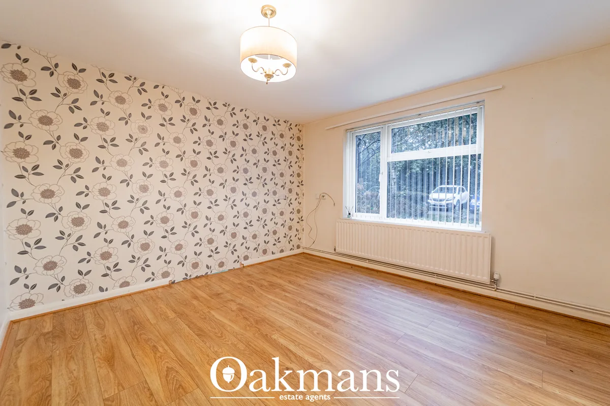 Spacious bedroom with floral patterned wallpaper, wooden flooring, ceiling light fixture, radiator and large window with