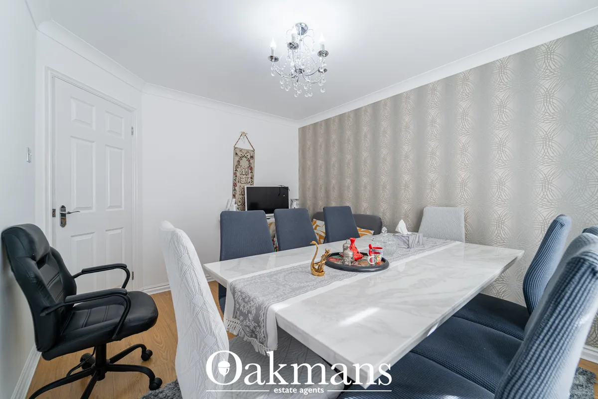 Spacious dining room with marble table, mixed seating, patterned wallpaper, crystal chandelier and wooden flooring