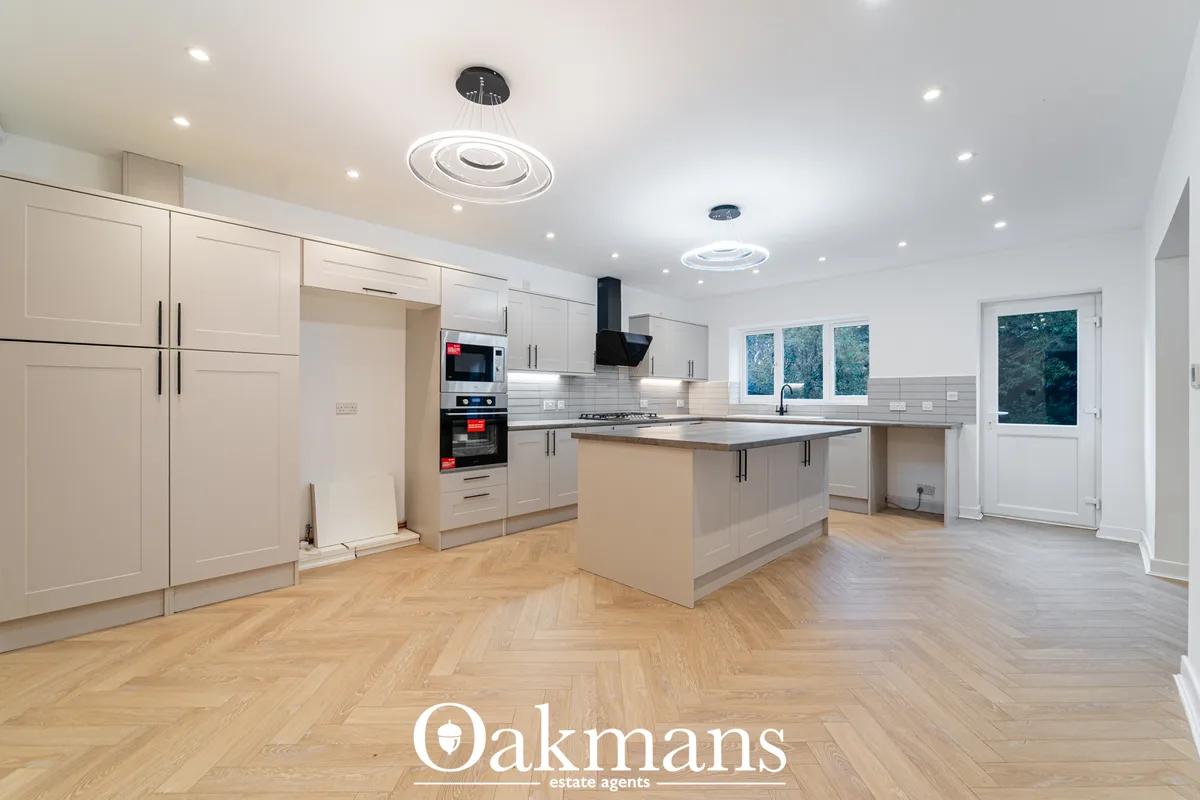 Modern fitted kitchen with cream cabinetry, stainless steel appliances, white subway tile splashback, central island wit