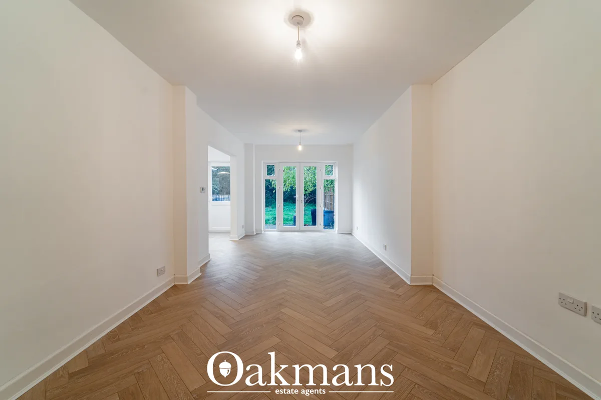 Bright hallway with herringbone wood flooring, white walls, ceiling lights, and glazed doors opening to garden views