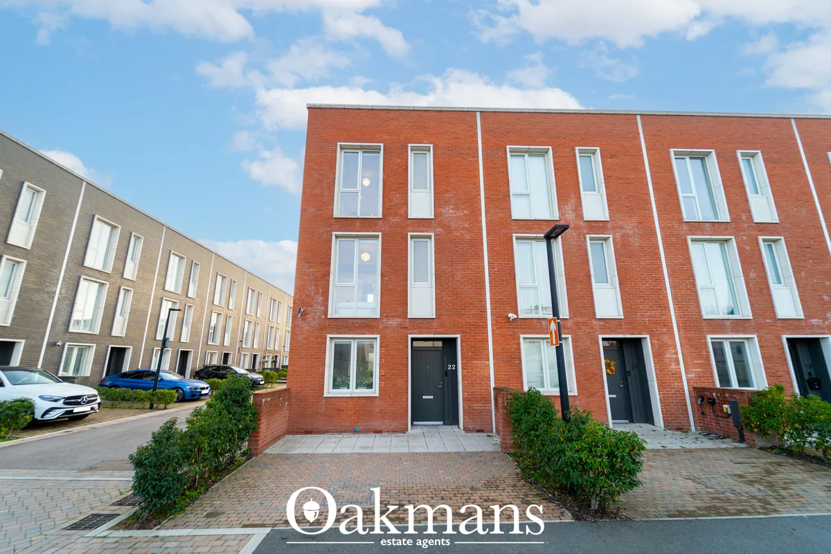 Modern red brick townhouse with three storeys, white framed windows, black entrance door numbered 22, and manicured hedg